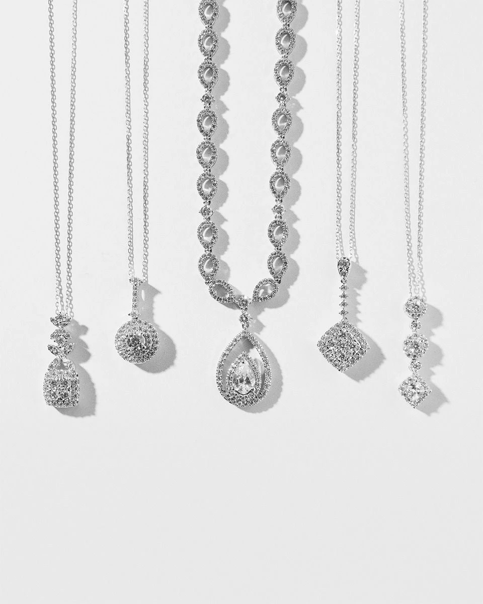 Diamond necklaces and pendants arranged on a white surface