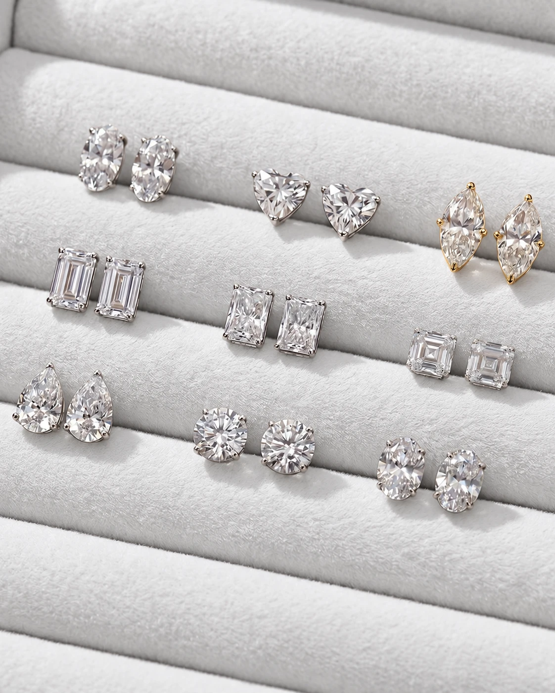 Diamond stud earrings in assorted shapes on a light jewelry tray