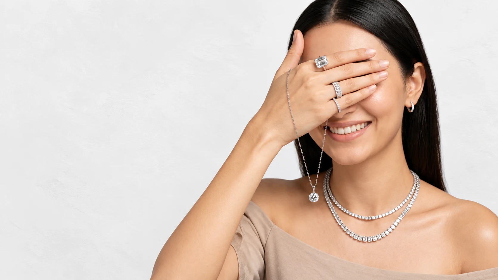 Woman smiling with diamond necklaces, rings and earrings